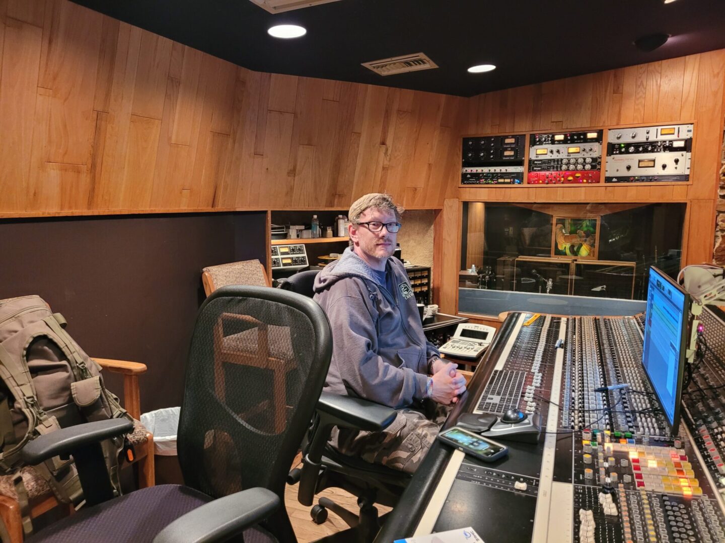 A man sitting at the front of an audio mixing board.