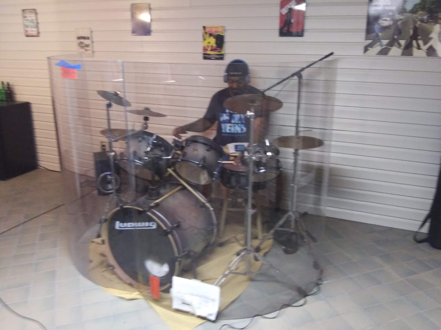 A man playing drums in front of a wall.