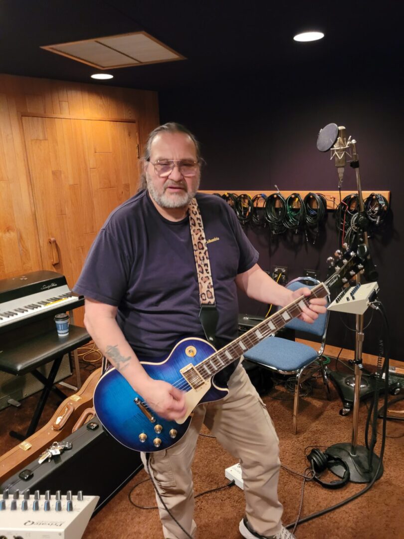 A person playing the guitar inside a studio or room.