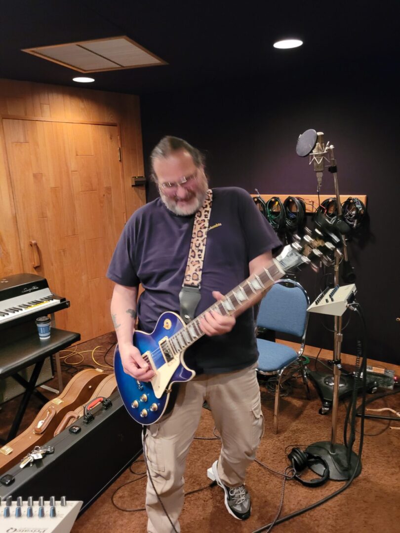 A person playing the guitar inside a studio or room.